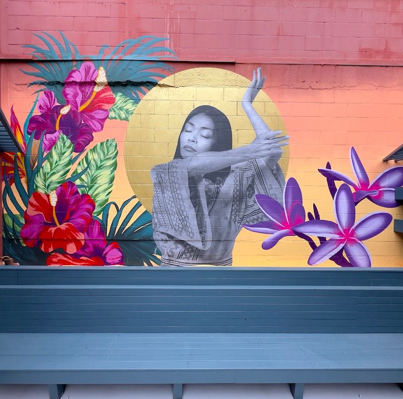 Mestiza mural with a woman posing with tropical flowers by Cheyenne Randall.