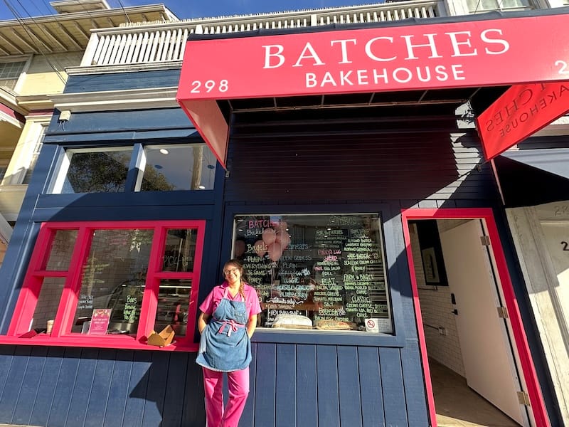 Ashlee Thompson of Batches Bakehouse in front of the pink and blue building