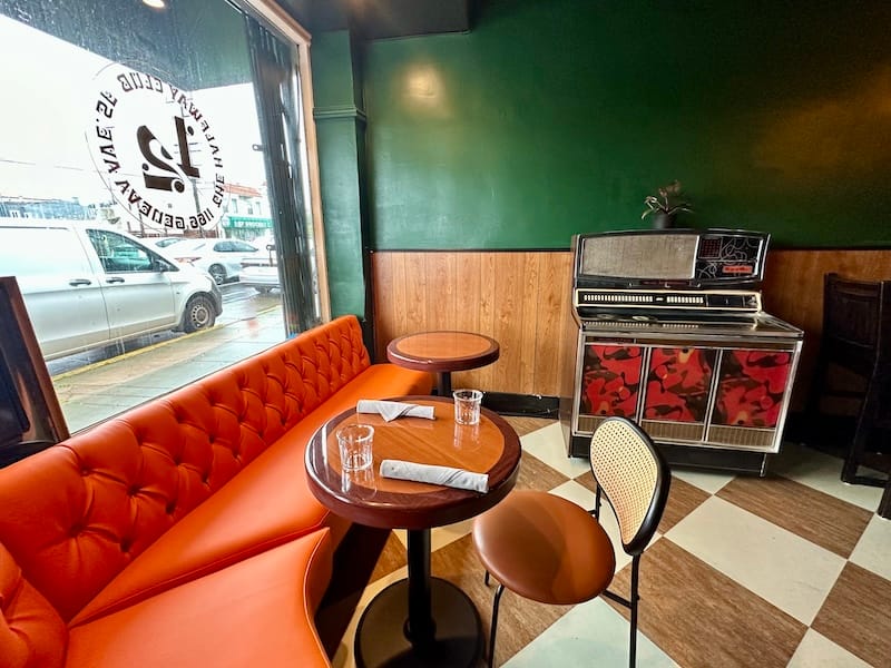 The front bar area of The Halfway Club with a jukebox and orange banquette