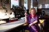 Marcia Gagliardi sitting at the bar at NOPA restaurant holding a glass of Champagne.